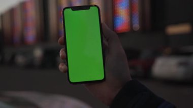 NEW YORK - 19 Nisan 2019: Yavaş çekim adamı el ele tutuşurken, şehrin arka planında dikey yeşil ekranlı akıllı telefon kullanın.