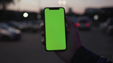 NEW YORK - 19 Nisan 2019: Geceleyin adam el ele tutuşurken dikey yeşil ekranlı, arka plan aydınlığı araba iletişim cihazı dijital cihaz, dokunmatik ekranlı, yavaş çekimde trafiği kapatan akıllı telefon kullanın