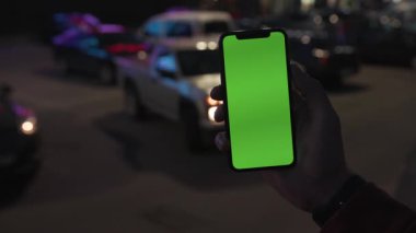 NEW YORK - 19 Nisan 2019: Gece vakti elinde akıllı telefon ile dikey yeşil ekran arka planda araç iletişim cihazını dijital cihaz, mobil dokunmatik mobil, yavaş çekim