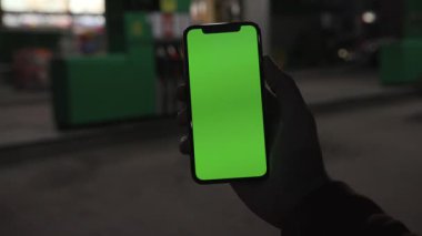 NEW YORK - 19 Nisan 2019: Elinde akıllı telefonu olan adamı kapat ve gece yarısı yeşil ekranlı, dikey yeşil ekranlı bir telefon kullan.