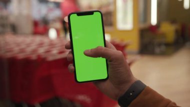 NEW YORK - 19 Nisan 2019: Gece şehir renkli ışık arka plan benzin istasyonu iletişim cihazı üzerinde dikey yeşil ekranlı akıllı telefon kullanan erkek elleri dijital cihaz mobil dokunmatik mobil yavaş çekim