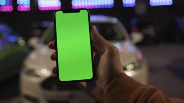 NEW YORK - 19 Nisan 2019: Gece şehir renkli arka plan beyaz araba iletişim aygıtı üzerinde dikey yeşil ekranlı akıllı telefon kullanan erkek elleri dijital cihaz mobil dokunmatik mobil yavaş çekim