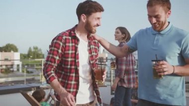Çekici genç erkek arkadaşlar eğlenceli sohbetler yapıyorlar birlikte meyve suyu içiyorlar şehir merkezindeki güzel terasta piknikte dinleniyorlar..