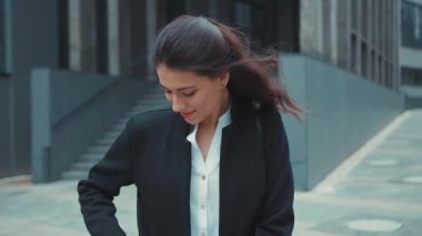 Beyaz tenli çekici ofis kızı modern binanın dışında yürüyor. Akıllı telefon uyarılarını kontrol ediyor. Haberler şok edici görünüyor..