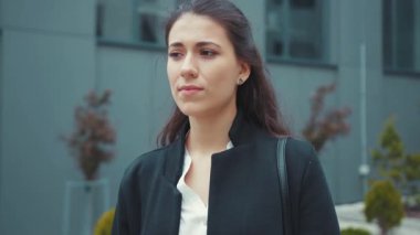 Genç ve güzel bir kadın yönetici ofis binasının önünde duruyor baş ağrısı çekiyor tapınaklara masaj yapıyor uzun çalışma saatlerinin etkilerini hissediyor. Çok çalıştım. Sağlık Hizmetleri.