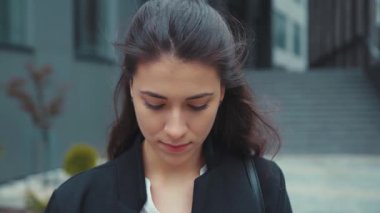 Güzel sakin esmer kadın portresi. Beyaz kız. Rüzgarlı bir günde iş yerinin dışında duruyor..