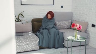 Evdeki kadın battaniyeye sarılı köpek gribi yüzünden acı çekiyor. Hasta kız battaniyenin altında kanepede uzanıyor ve köpekle ateşini ölçüyor. Titreyen ve hasta bir grip hastası genç Asyalı kadının eve yakın çekimi. Salgın 2019 Coronavirüs 2019-nCoV Konsepti.