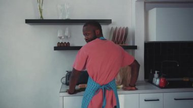 Günlük kıyafet giymiş biri modern ve çağdaş bir mutfak ortamında lezzetli bir yemek hazırlıyor.