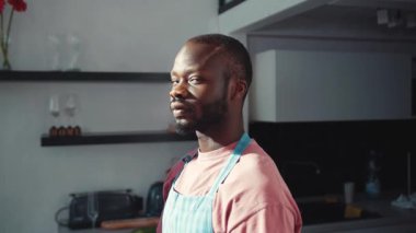 Çekici, sıradan bir adamın portresi mavi önlük giymiş kameraya sevinçle gülümseyen bir şef. Mutfağın içi. Daire. Mutlu aşçı çocuk. Evde kalıyorum..