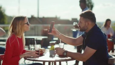 Gülümseyen genç adam ve kadın kokteyl içerken hamburger yerken sokak kafesinde telefon kullanırken yemek yerken kız arkadaş yemek yerken neşeli bir portre ağır çekim