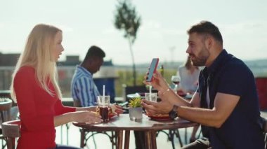 Çirkin genç bir kadın, adamla konuşuyor. Telefonda, kafede fotoğraf çekiyor. Birlikte yemek yiyor, yemek yiyor, yavaş çekimde resim çekiyor.