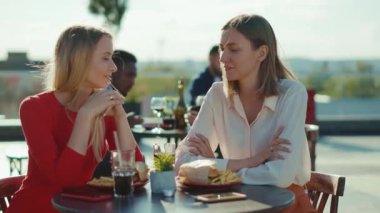 İki güzel kadın dinleniyor, kokteyl içiyorlar. Kafe caddesinde burger yiyorlar. Kafe şehir arkadaşlığı modelleri açık havada ağır çekimde.