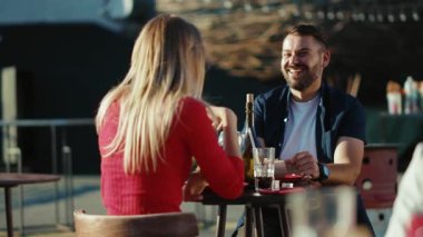 Mutlu genç adam ve kadın, sokak kafesinde kokteyl içerken birlikte gülerlerken, yemek yerken, kız arkadaş yemek yerken, ağır çekimde neşeli portreler çekerken.