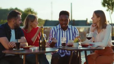 Çekici mutlu arkadaşlar sokak kafeteryasında buluşup kokteyl içerken gülümsüyor hafta sonu şehir partisi arkadaşlığı şenliği yavaş çekimde konuşuyor.
