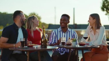 Gün ışığında mutlu arkadaşlar buluşur ve kokteyllerini içerler sokak kafesinde gülümserler hafta sonu şehir partileri arkadaşlığı şenlikleri yavaş çekim konuşmaları.