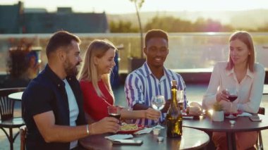Mutlu arkadaşlar buluşur ve kokteyl içerler sokak kafesi manzarasında gülümserler hafta sonu şehir partileri tatil arkadaşlığı şenlikleri yavaş çekim konuşmaları