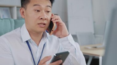 Müşterilerle telefonda konuşan odaklanmış genç iş adamının portresi. Asyalı erkek profesyonel çağrı merkezi temsilcisi, müşteri destek müdürü veya telefon aracılığıyla iletişim kuran pazarlamacı..