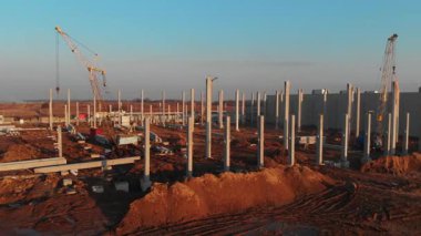 Modern inşaat alanının sinematik gün batımı manzarası. Yeni fabrika geliştirme sanayi bölgesi inşa ediliyor. Çimento ve mermer binalar. Hava görünümü.