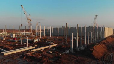 İnşaat alanında İHA uçuşu. Günbatımında yeni modern endüstriyel üretim alanı fabrika geliştirme istasyonu.