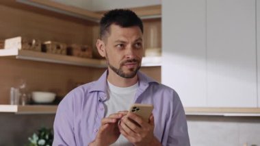 Güzel görünümlü beyaz iş adamını sıradan giysiler içinde bir kızla sohbet ederken, flört uygulaması kullanırken çekmek. Gülümseyen genç adam arka plandaki akıllı telefon ekranına bakıyor. Şehir manzarası harika.