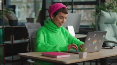 Mutlu, heyecanlı, genç transseksüel kişi dizüstü bilgisayarla çalışırken iyi haberler aldı.