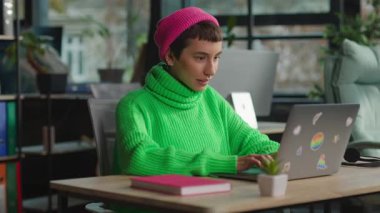 İçerde dizüstü bilgisayarın başında oturan neşeli, şaşkın, duygusal olmayan kişi.