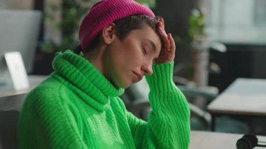 Ofiste dizüstü bilgisayarla çalışırken baş ağrısı çeken travesti.