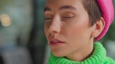 Kameraya piercing takmış, gülümseyen, beyaz olmayan birinin yakın çekimi.