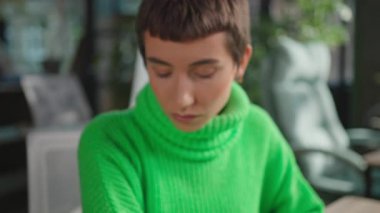 Gökkuşağı küpeli ve kameraya bakan ikili olmayan kişinin yakın plan portresi.