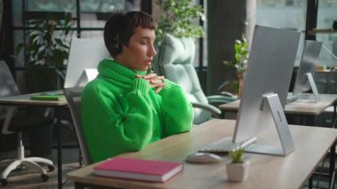 İş yerindeki çağrı merkezinde müşterilere yardım eden kulaklıklı eşcinsel bir kadının fotoğrafı.