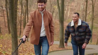 Homoseksüel gülümseyen çok kültürlü çift parkta beyaz köpeğe tırmanıyor.