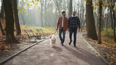 Sonbaharda parkta köpekle konuşan ve gezen çok ırklı eşcinsel çifti çekmek