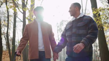 Birbirine aşık iki adamın el ele tutuşup doğada yürümesi.