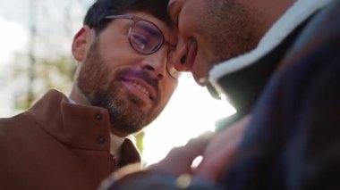 İki gülümseyen, etnik çeşitlilikte sakallı adam açık havada duygularını gösteriyor.