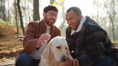 Çift cinsiyetli, çok ırklı, gülümseyen ve evcil hayvanlarla vakit geçiren bir çift.