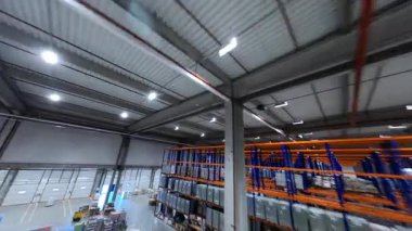 FPV helikopter görüntüsü deponun içini gösteriyor. Lojistik parkı. Teslimat malları olan büyük ürün dağıtım merkezi binası. Çalışanlar.
