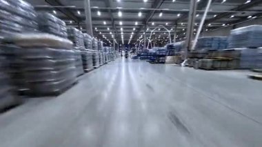 FPV görüntüleri büyük endüstriyel depo lojistik merkezi binasının içini gösteriyor. İşçiler malları yükleyip boşaltmakla meşguller. Ürün dağıtımı.