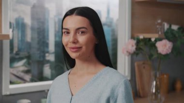 Evdeki mutfakta kameraya bakan mutlu, gülümseyen kadın. Kendinden emin. Rahat ol. Modern daire. Portre. Yavaş çekim