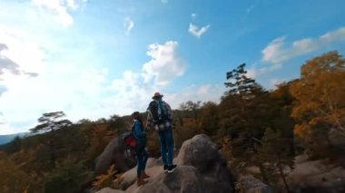 Genç aktif yürüyüşçülerin FPV görüntüleri muhteşem manzaraları gözlemlemek için kayalara tırmanıyor. Seyahat güzergahı. Olağanüstü bir yürüyüş. Doğa ortamı.