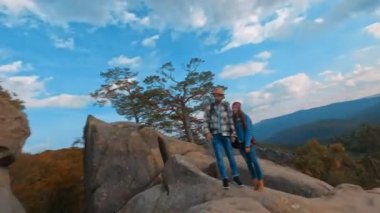 Manevra kabiliyeti olan FPV kameraları kayalıklarda gezen ve turistik yerleri araştıran genç ve aktif beyaz bir çiftin görüntüleri. Dovbush Kayaları. Ukrayna 'nın hedefi.