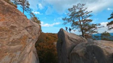İlham verici bir doğa. Dovbush Kayaları. Kafkasyalı genç turist çift dağın zirvesine tırmanıyor. Yürüyüş aktivitesi. Olağanüstü bir macera. Heyecan.