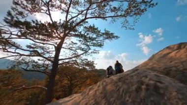 Seyahat yeri. Sinema ormanı dağ manzarasının muhteşem FPV görüntüsü. Kayalara tırmanan maceraperest bir çift..