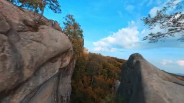 Dovbush Kayaları. Genç hippi erkek hippinin kayalıkların tepesine tırmandığı sinematik FPV sahnesi. Olağanüstü bir yürüyüş. Aktif turizm. Seyahat.