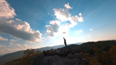 Sinema ilham veren doğanın insansız hava aracı çekimi. Vahşi kayalar ve orman manzarası. Dağın tepesine atlayan etkin bir turist..