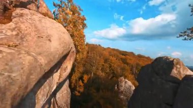Sonbahar manzarası. Renkli orman ağaçları arasında sinematik kayaların ilham verici görüntüsü. Hava çok güzel. FPV hava görüntüleri.