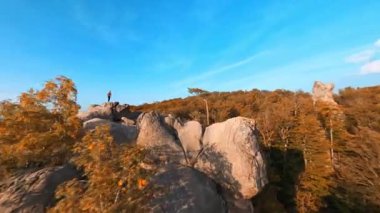 Manevra kabiliyeti olan FPV uçuşu Dovbush kayalarının etrafında. Muhteşem Ukrayna seyahat yeri. Yürüyüş yapan turistler kayalıklara tırmanıyorlar. Özgürlük için. Aktivite. Seyahat.
