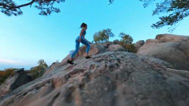 Genç aktif sporcu, dağın tepesinde koşuyor, kayalara tırmanıyor ve açık havada spor eğitimi alıyor. Dovbush Kayaları. Halk ve spor.
