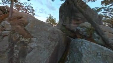 Uçan FPV çekimleri. Sinematik vahşi doğa manzarası. Genç sporcu kadın kayalara tırmanırken esnek jimnastik yapıyor. Aktivite. Sağlıklı yaşam tarzı.