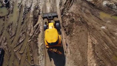 İnşaat alanından geçen sarı siyah kazıcı makinesinin yukarıdan görünüşü. Endüstriyel üretim ağır makineler, fabrika inşaatı. Endüstri. Hava aracı.