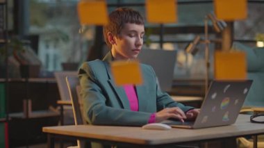 Modern ofis kadınlarında pembe saçlı kadınlar akşamları LGBT çıkartmalı dizüstü bilgisayar kullanırlar.